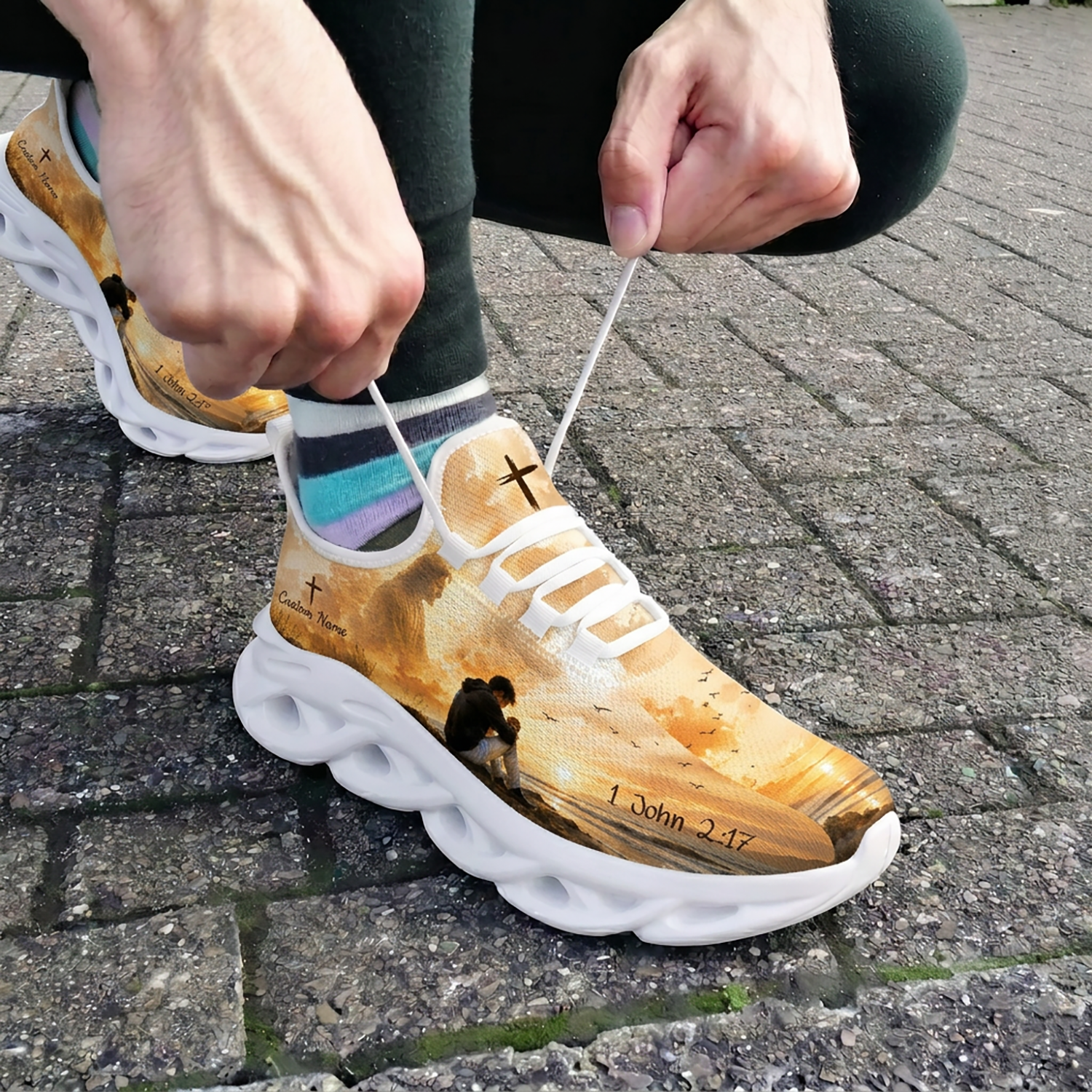 Close-up of a person tying white laces on the custom 1 John 2:17 shoes while wearing them outdoors on stone pavement