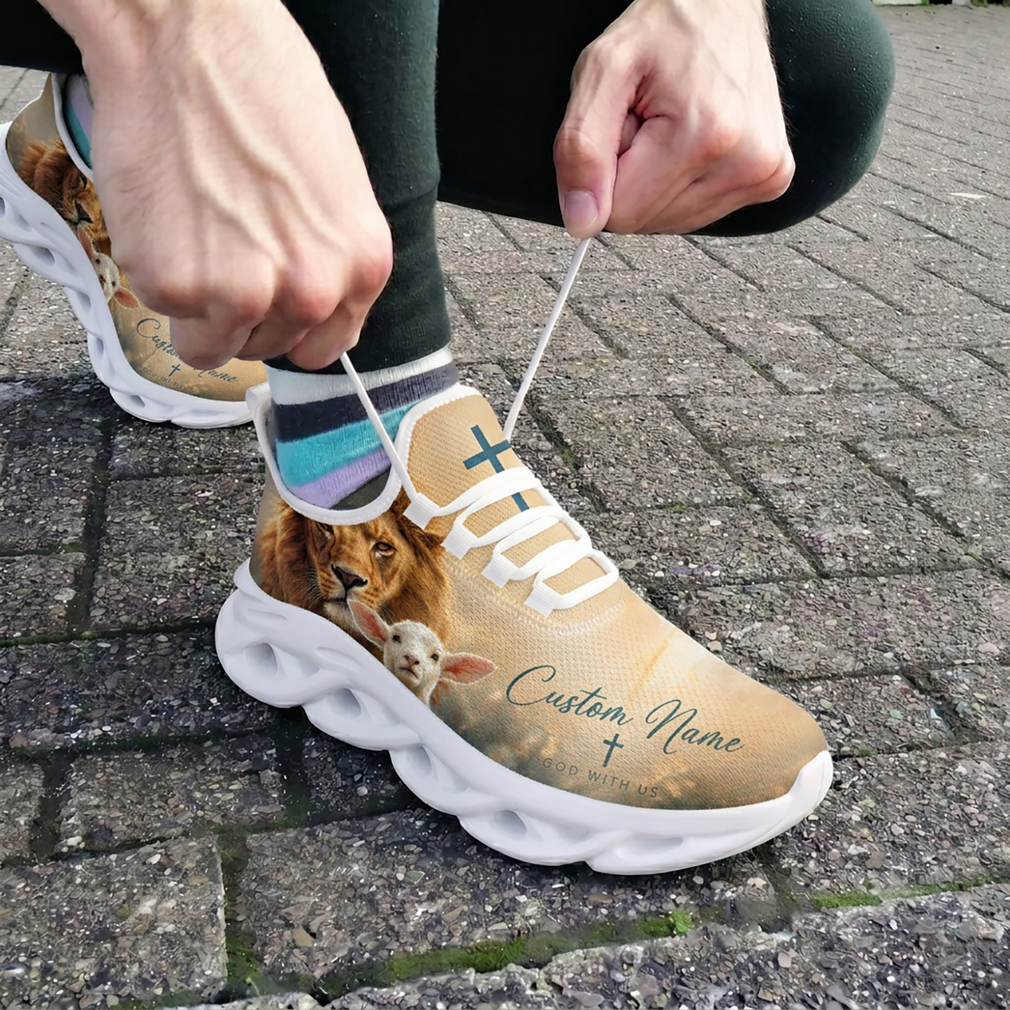 Close-up view of a person lacing up the white custom God With Us athletic shoes on an outdoor pavement background