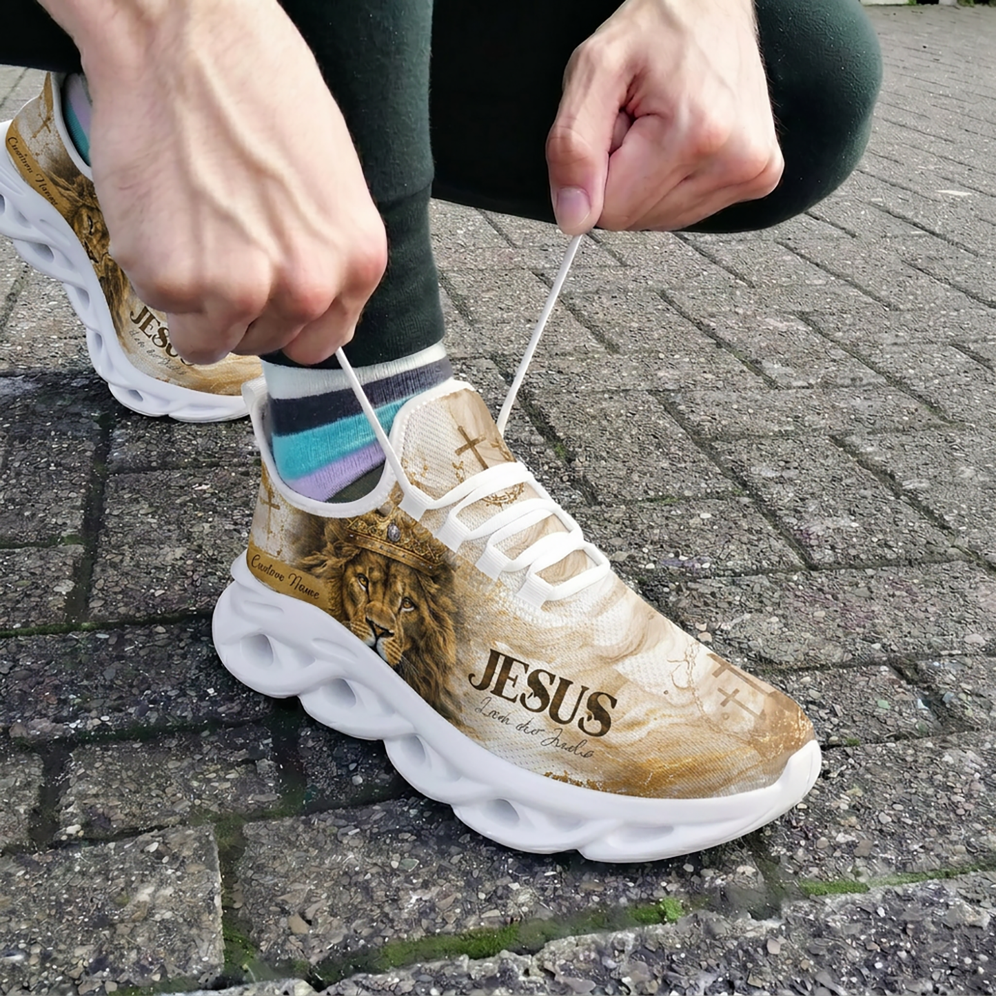 Close-up view of a person lacing up the custom Portuguese Lion of Judah athletic shoes outdoors