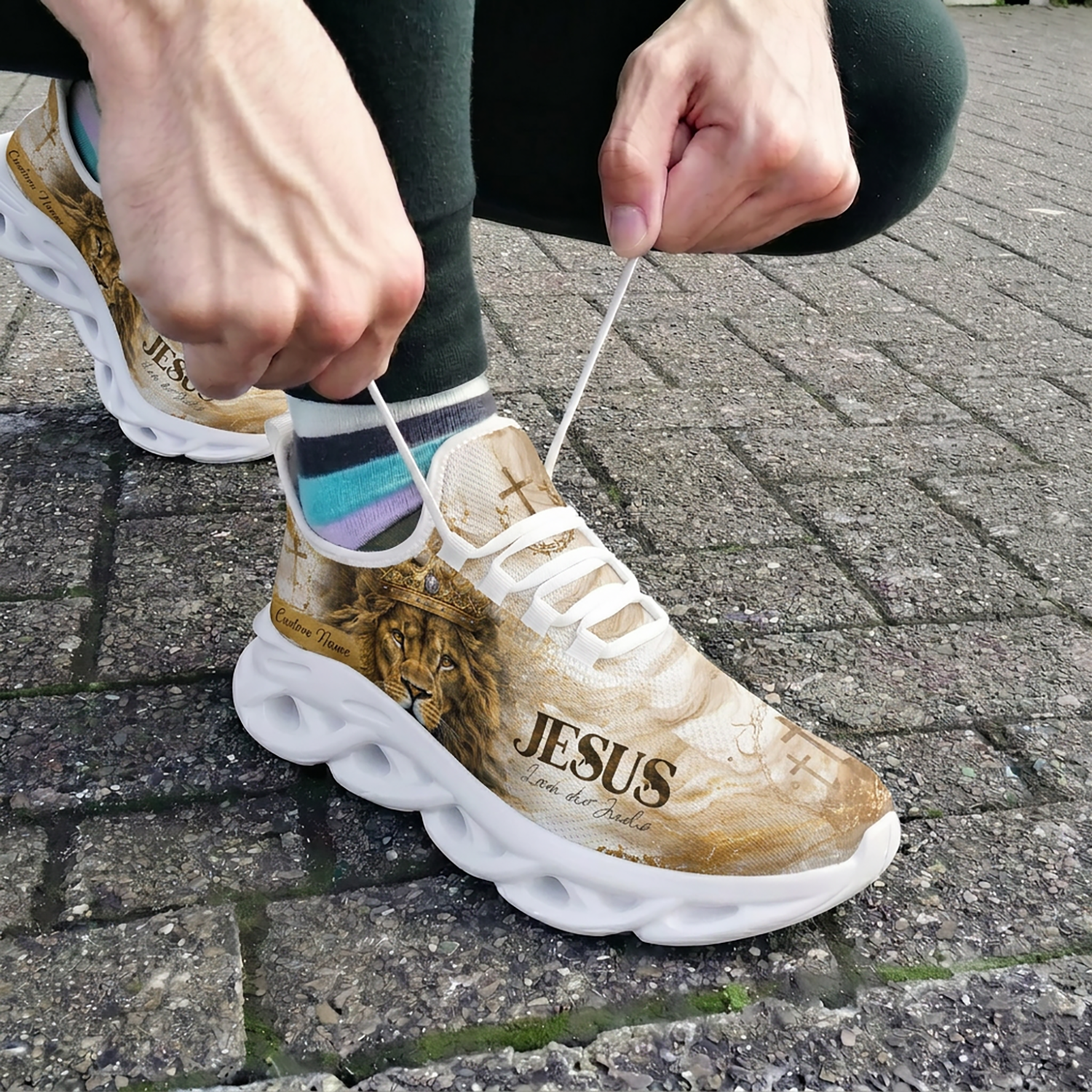 Close-up view of a person lacing up the custom Portuguese Lion of Judah athletic shoes outdoors