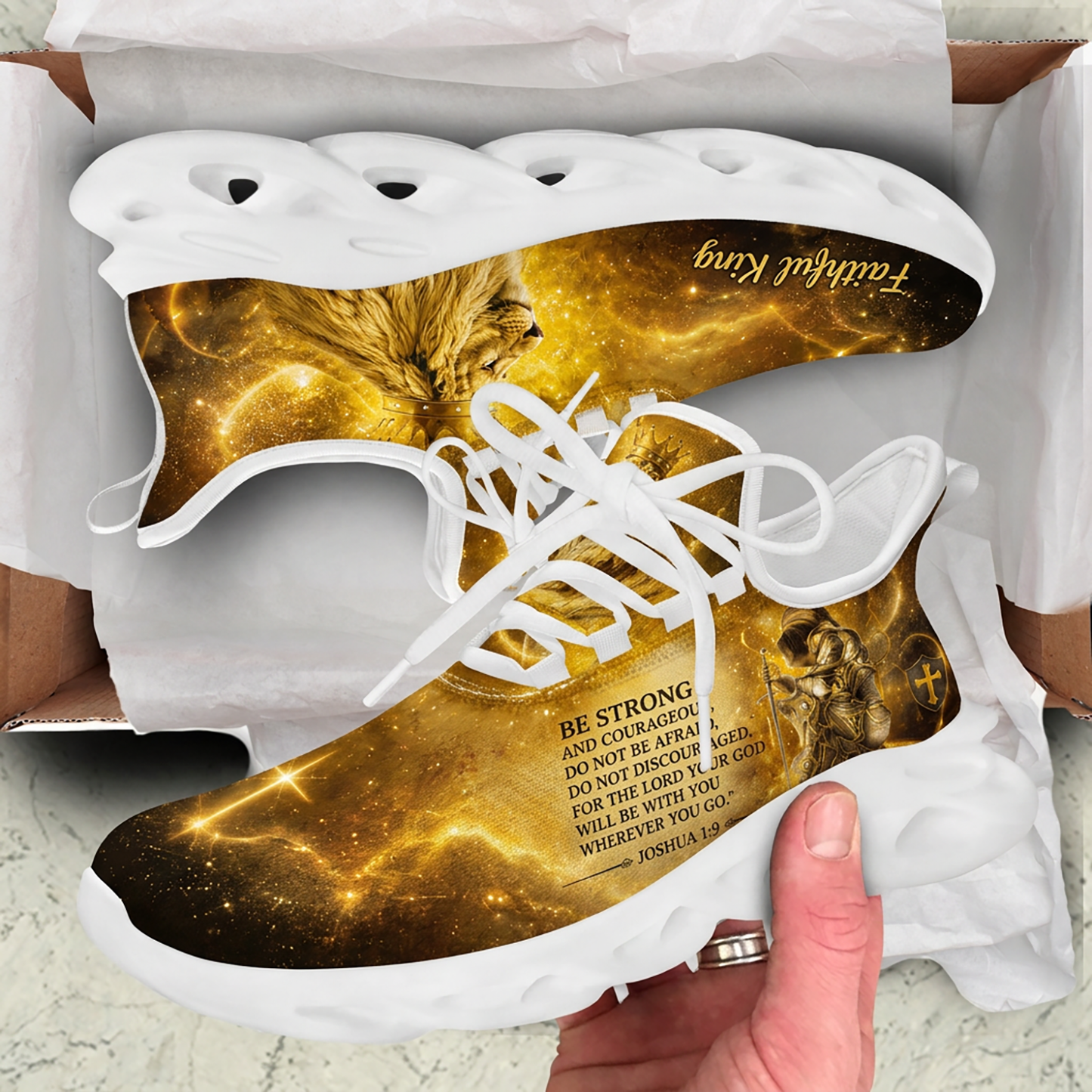 Unboxing presentation of the golden Christian sneakers inside a cardboard box displaying the Joshua 1:9 scripture text