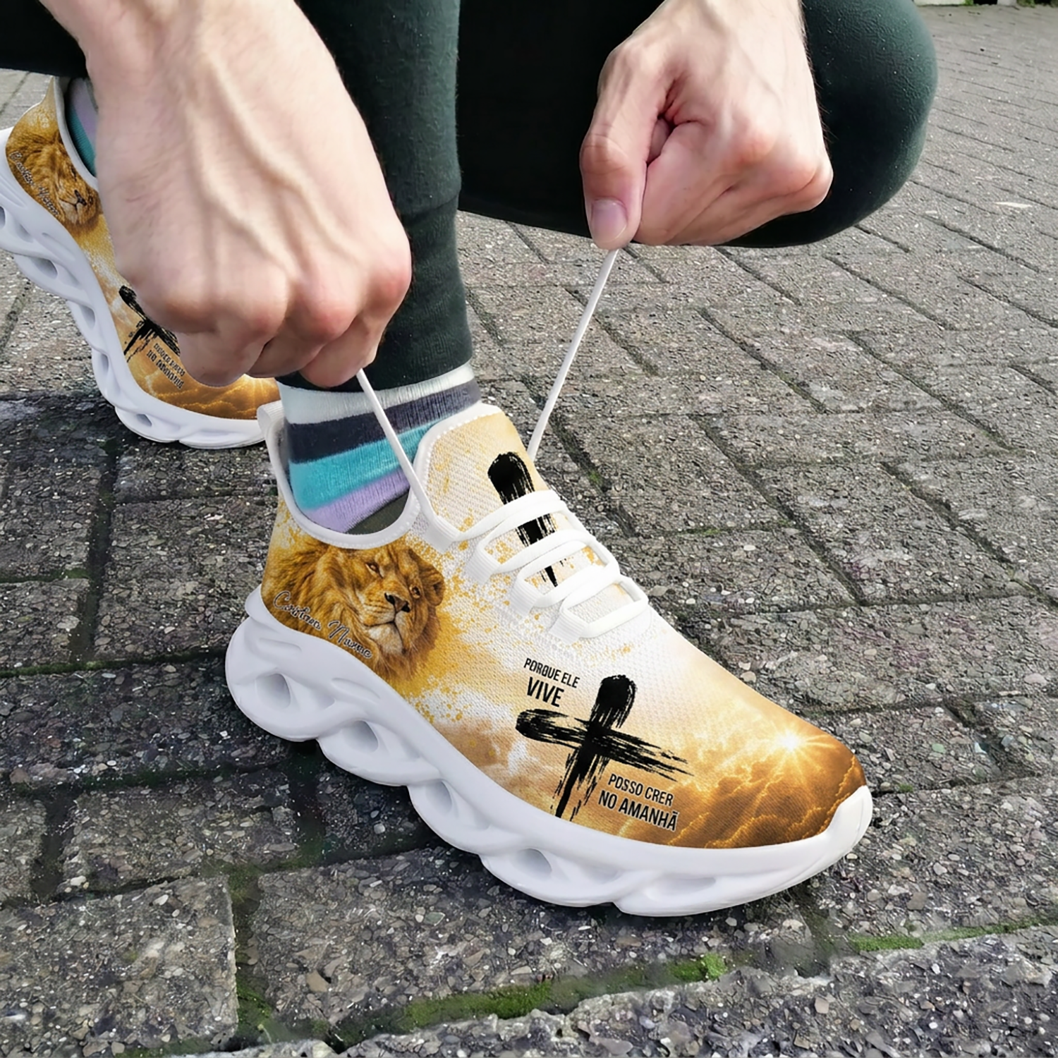 Close-up of a person tying the white laces of the custom Portuguese faith shoes out on a brick pavement background