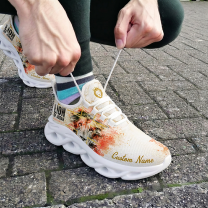 Close-up view of a person tying the laces of the white and orange-red paint splatter Christian shoes on outdoor brick pavement