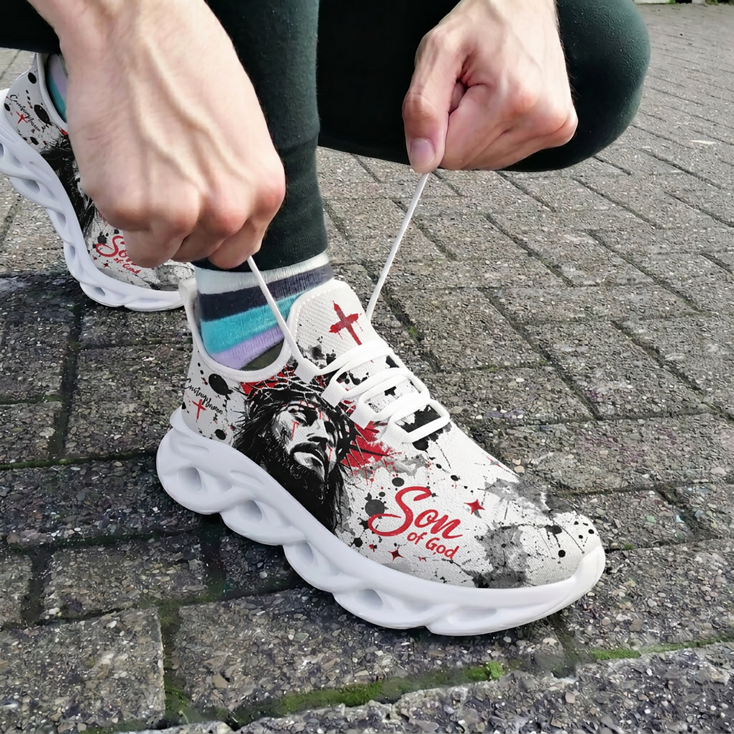 Close-up of a person tying the laces of the custom Jesus Christ Max Soul shoes on an outdoor brick pavement